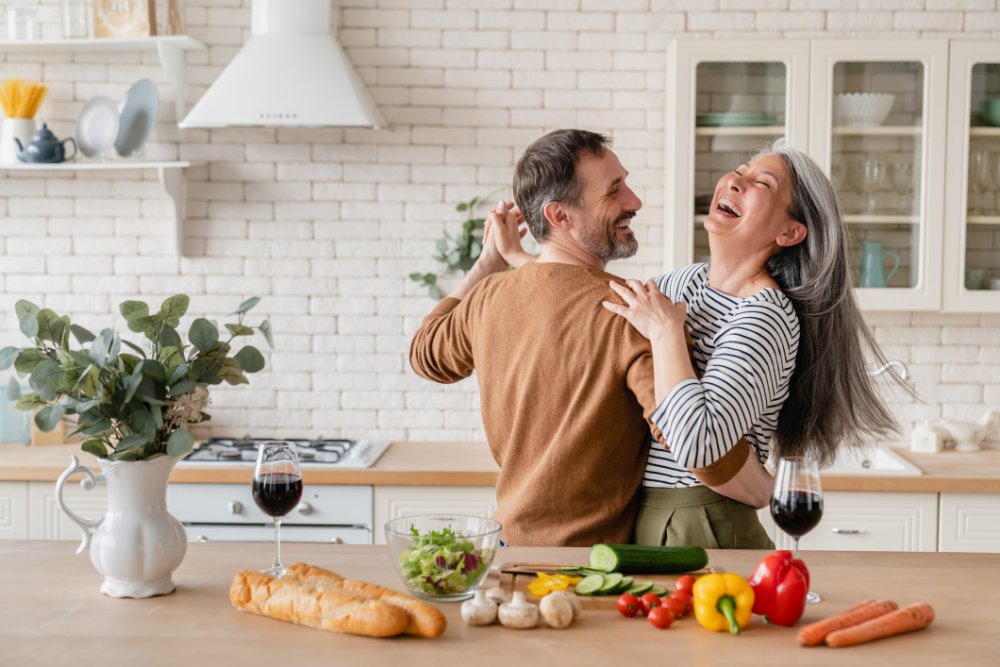 Happy cheerful middle-aged mature couple family parents dancing together in the kitchen